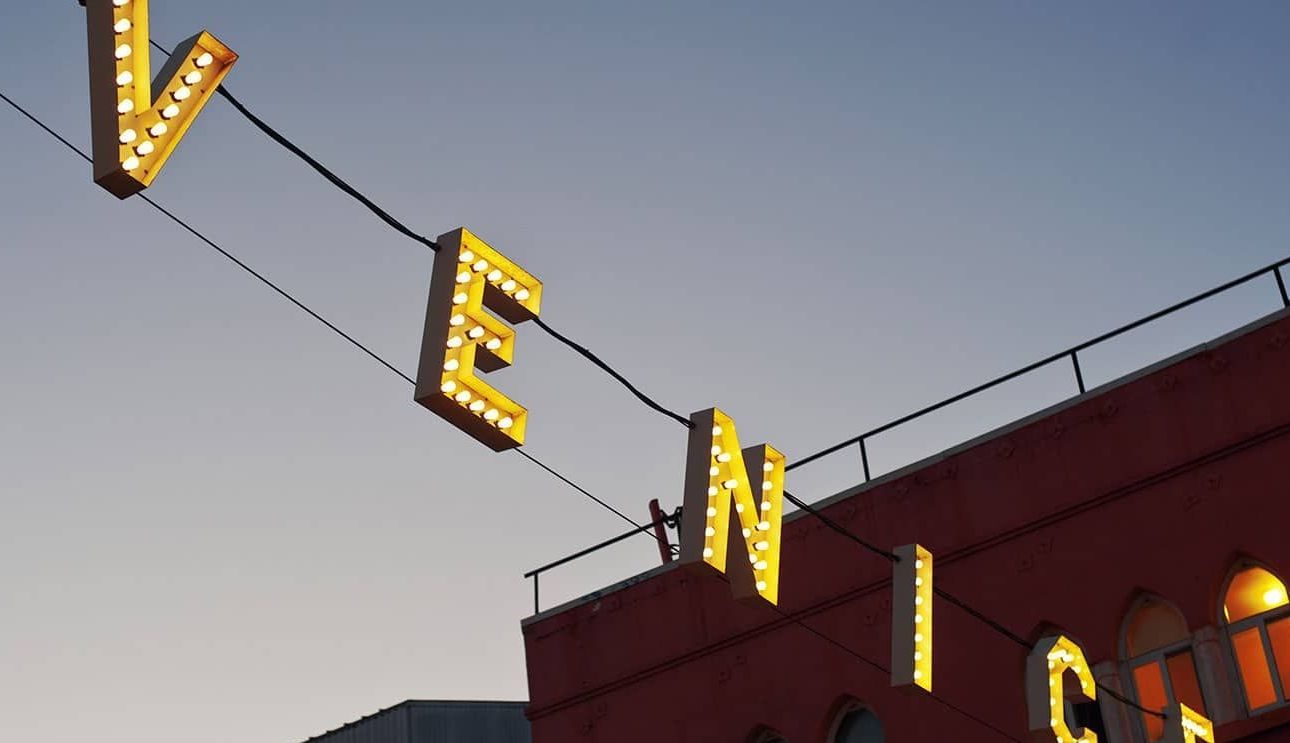 Venice sign glowing above a red brick building at dusk